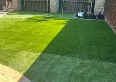 A lush green grass lawn surrounded by a stone fence and a stone wall, creating a serene outdoor space